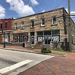 Downtown Lithonia, Georgia, with several stone buildings with signs for the businesses within them reading "Green Love Kitchen" and "Black Dot Cultural Center".
